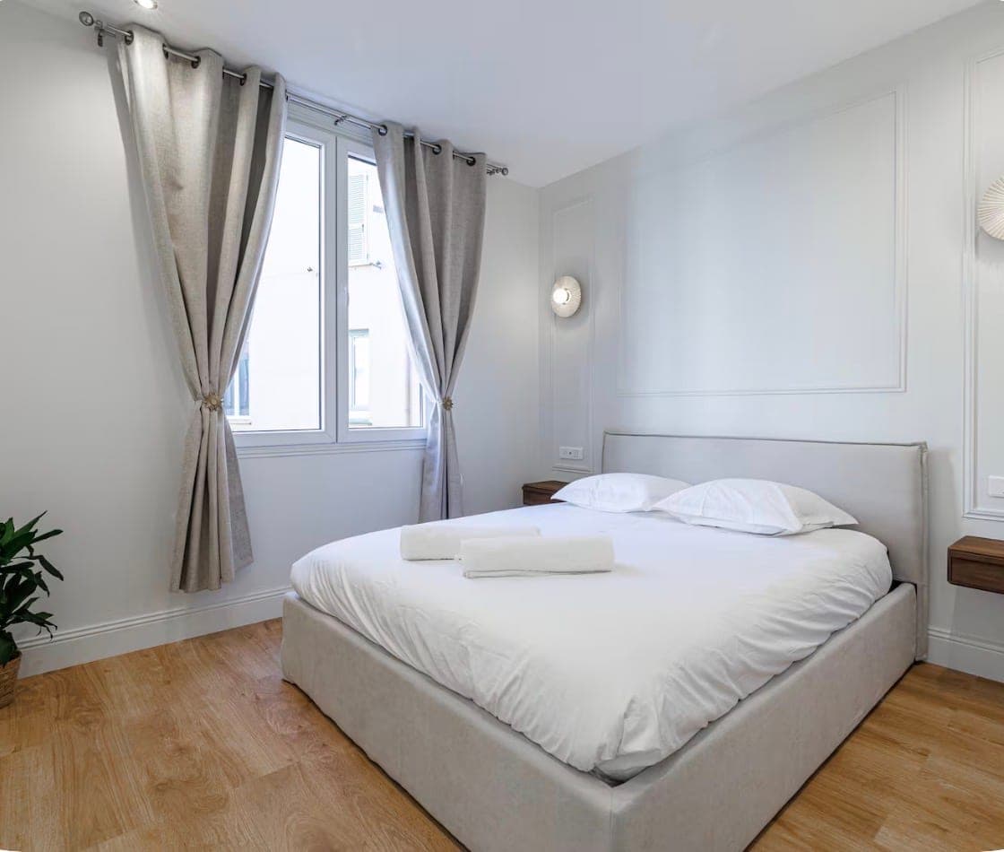 Chambre claire prête à accueillir, lit fait et serviettes disposées
