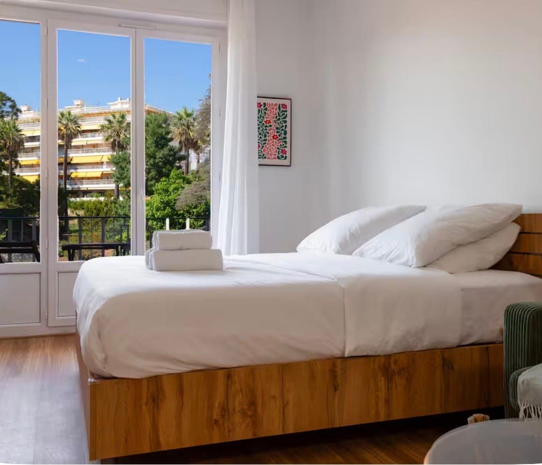 Chambre claire ouvrant sur un balcon avec vue sur les palmiers