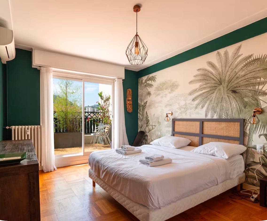 Chambre vert profond avec papier peint tropical et accès terrasse