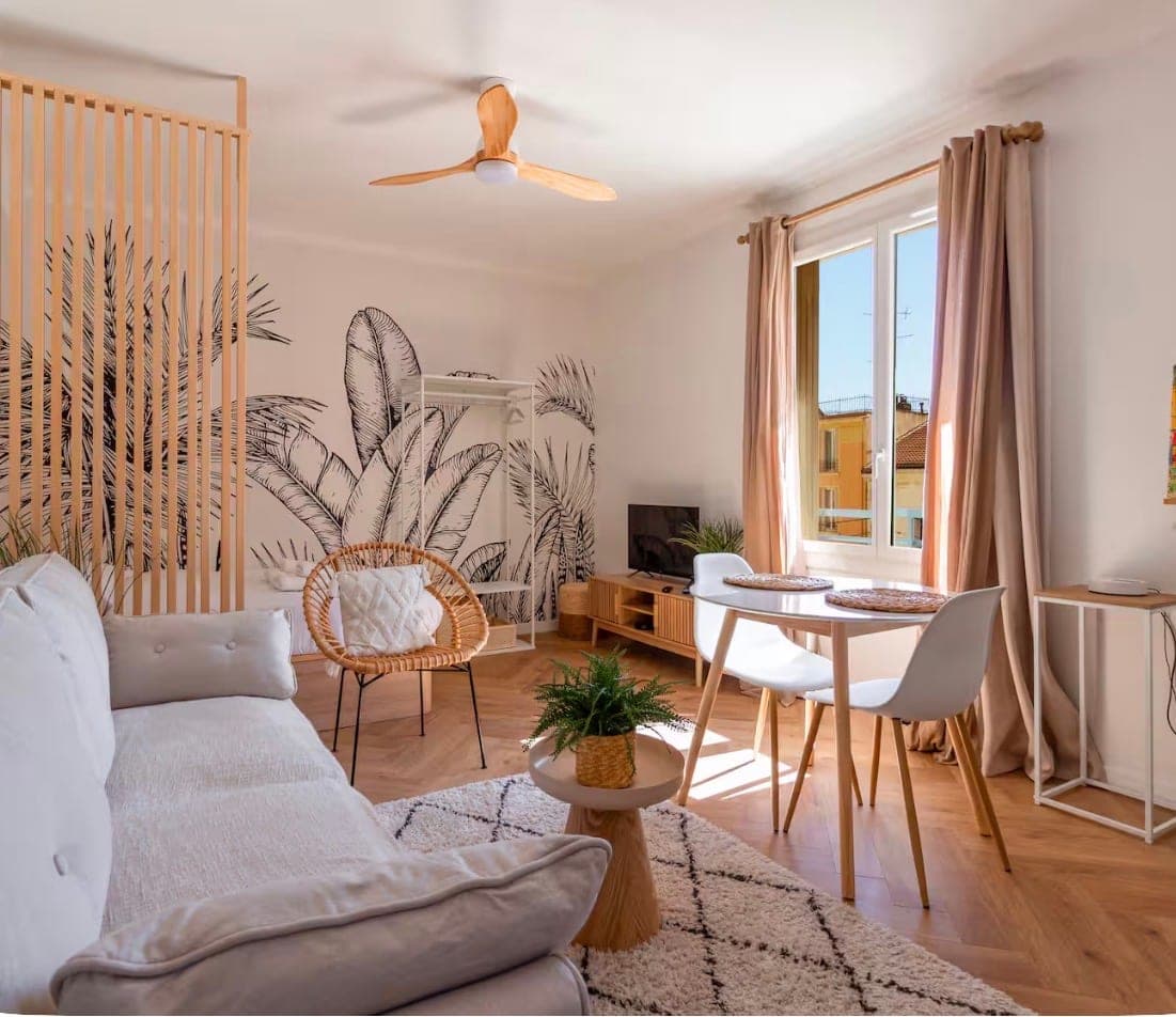 Séjour lumineux avec fresque végétale, coin repas et parquet à chevrons