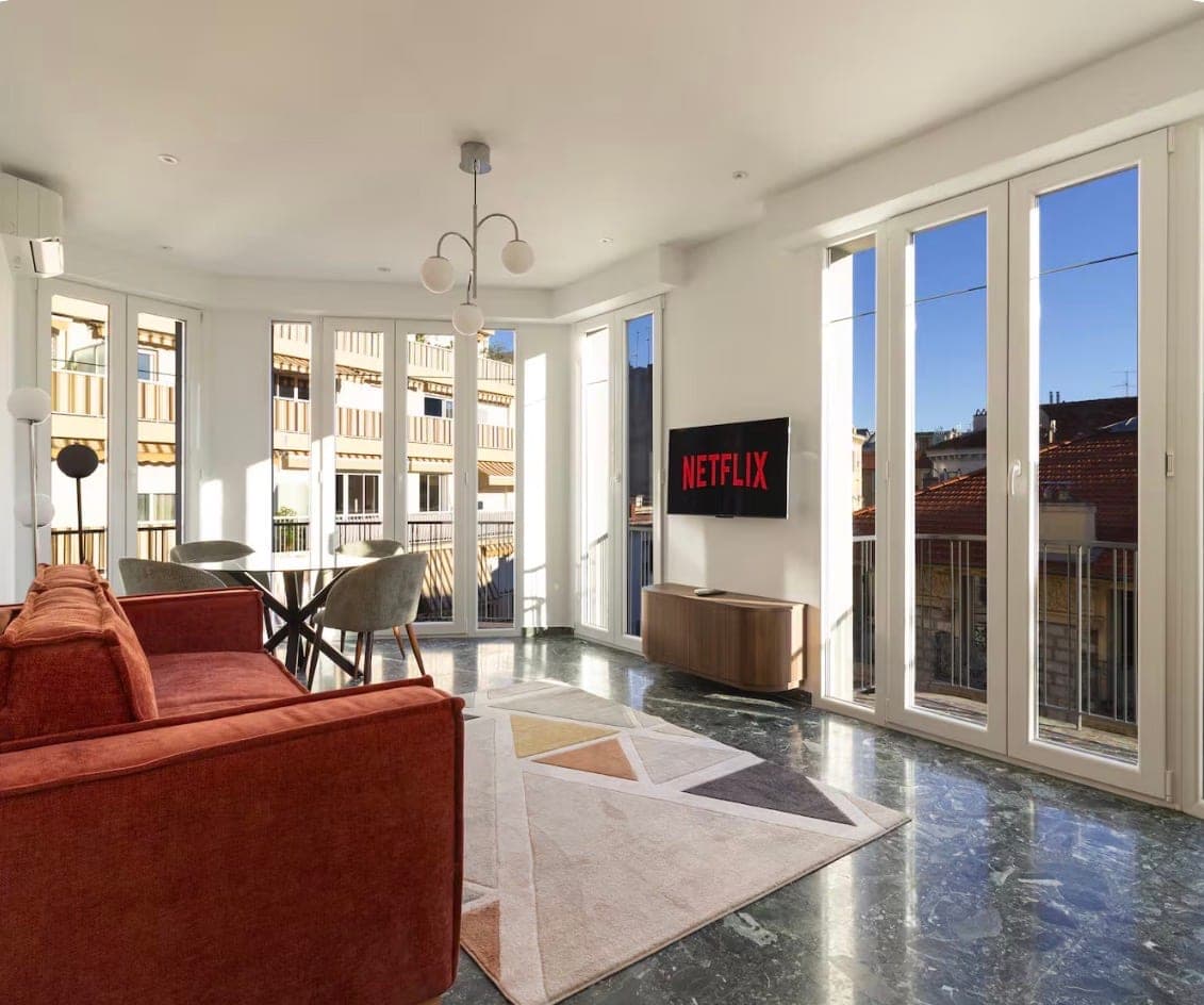 Séjour lumineux d’un appartement niçois géré par Azura, sol en granito et vue sur les toits