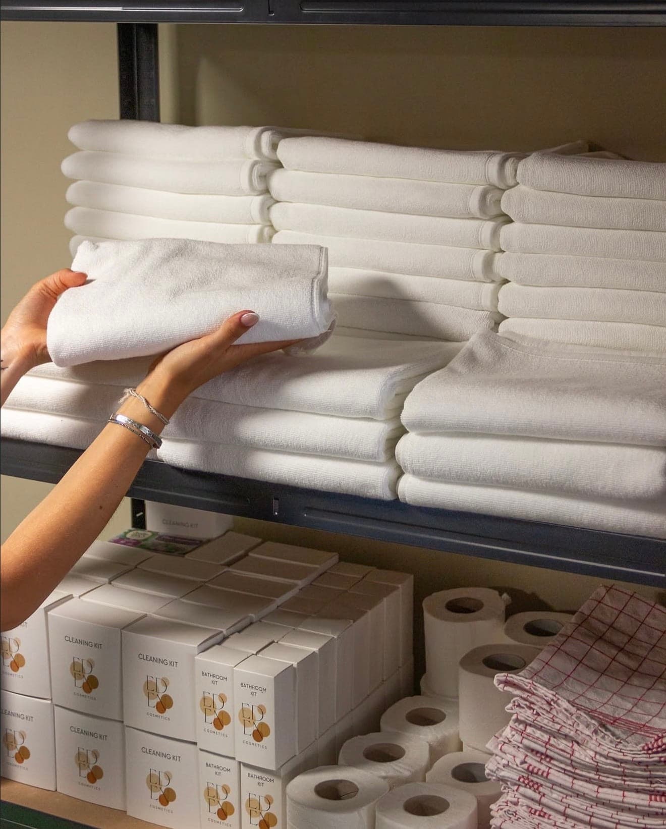Réserve de linge blanc et kits d’accueil rangés en rayonnage